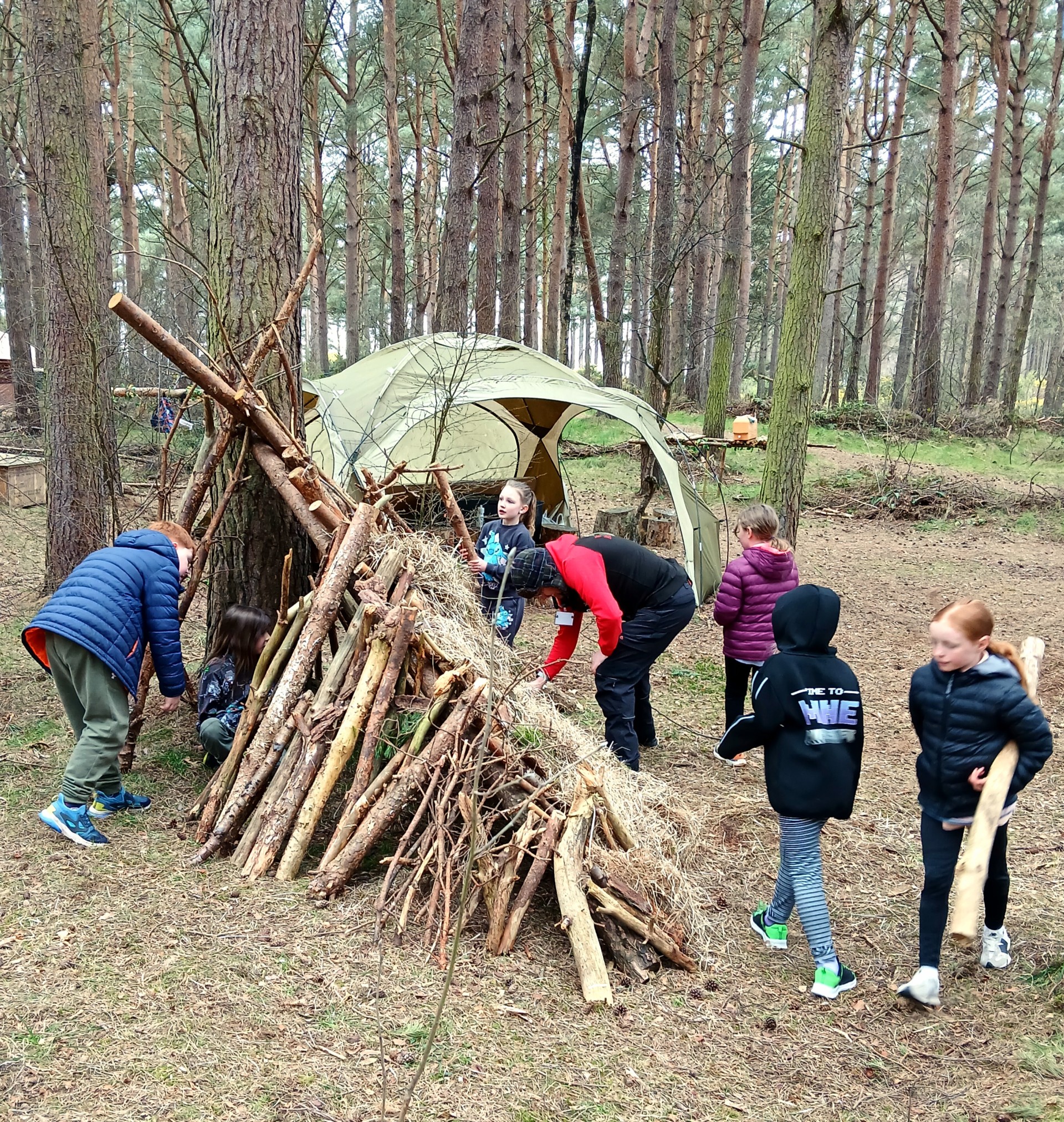 group of children enjoying shelter building in the woods